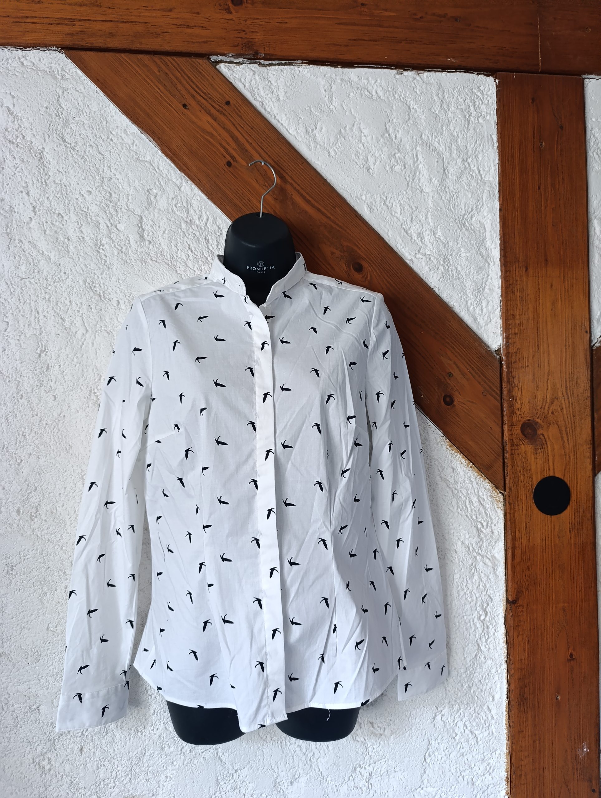 Vue de face d'une chemise blanche à motifs hirondelles noires sur un mannequin.
